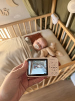 Numsy One babyfoon: ouderunit in de hand voor het bedje, klantfoto